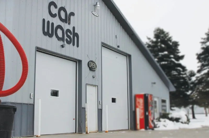 Grey steel car wash building with two white insulated washbay doors in winter