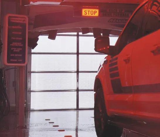 Car exiting a wash bay through an open Survivor polycarbonate door
