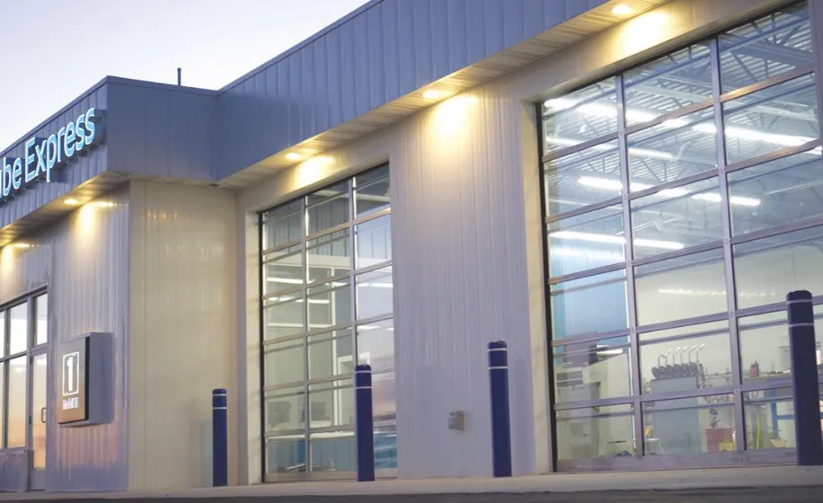 Modern quick-lube building at dusk with three lit UltraClear full-vision doors