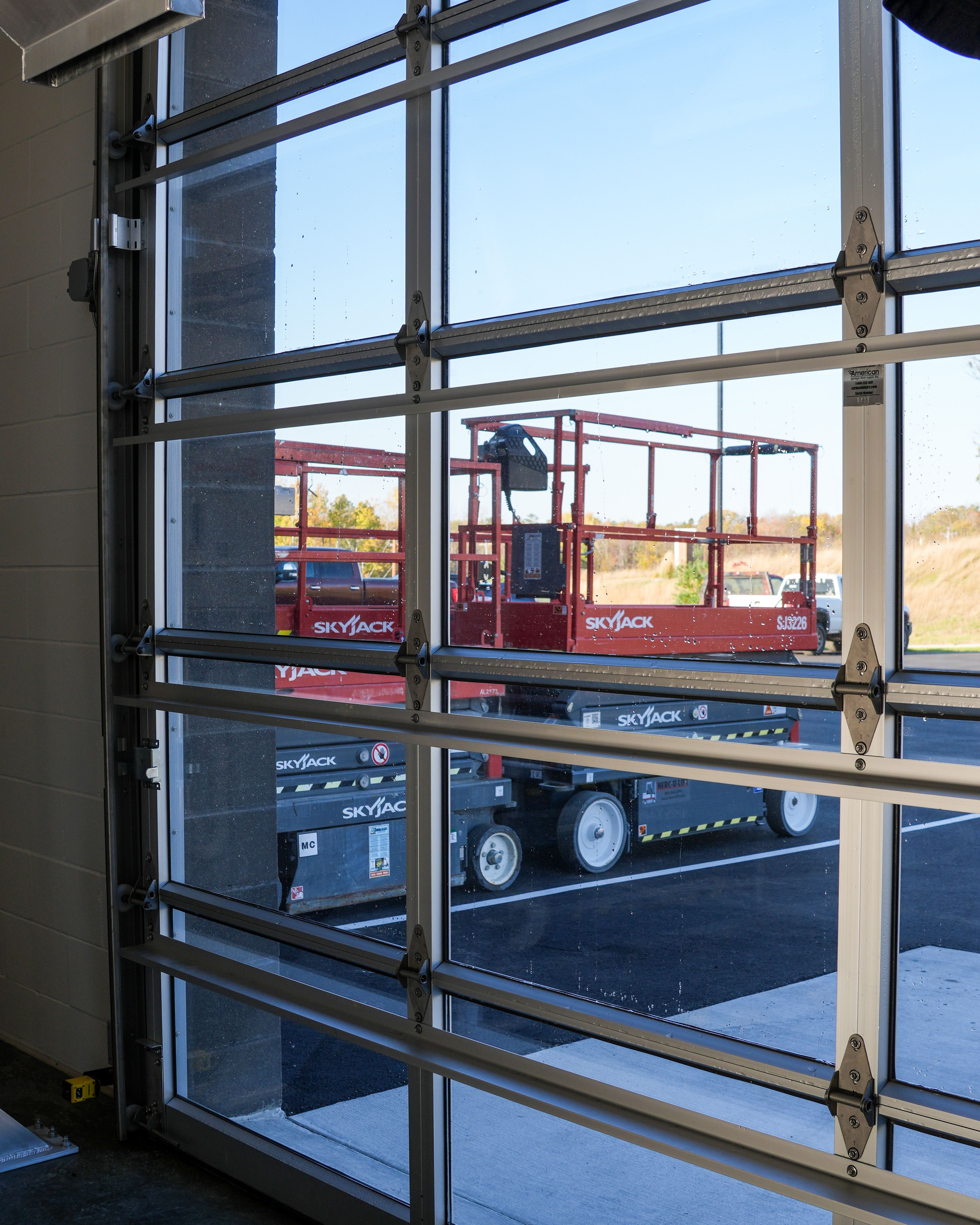 Close interior view of a full-vision door end stile with hinges, glazing, and the manufacturer serial label