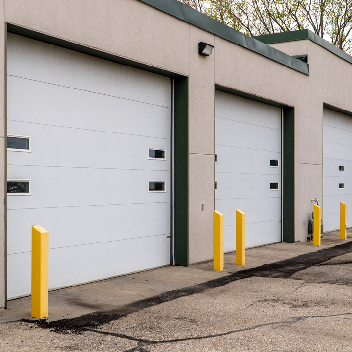 Reference exterior view of white insulated wash-bay overhead doors