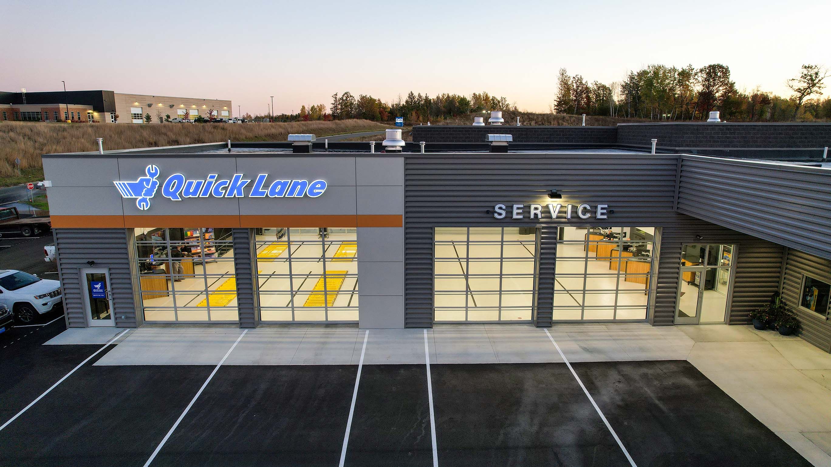 Quick Lane and service bay elevation at dusk with closed full-vision UltraClear doors lit from inside