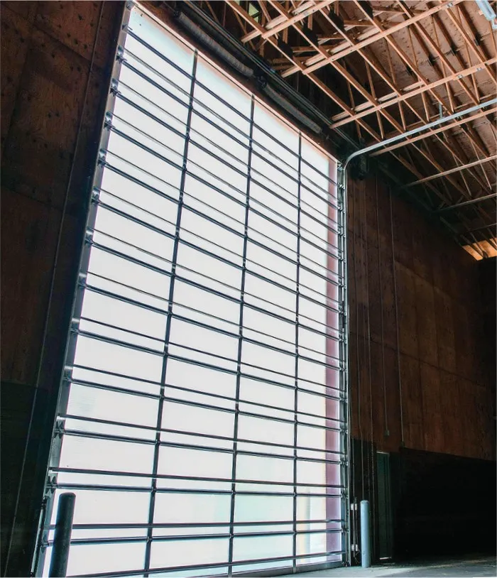 Interior view looking up at a very tall Goliath polycarbonate door in a timber and steel framed industrial building