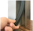 Hand pulling the removable weather stripping out of a stainless door frame